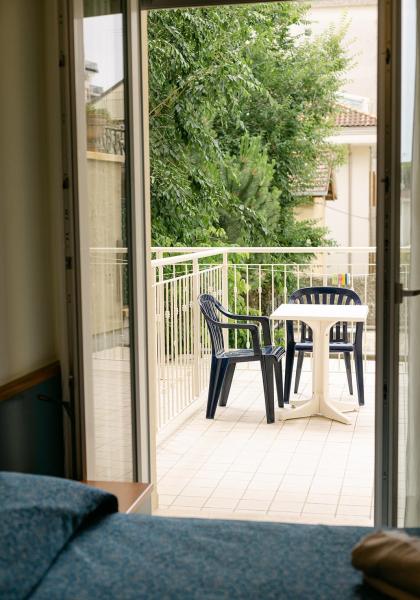 Balcony with chairs and table, overlooking trees.