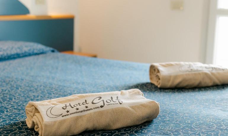 Chambre d'hôtel avec serviettes sur lit bleu.